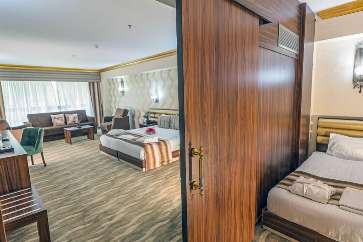 A hotel room with a bed, a sofa, a desk, and a chair.