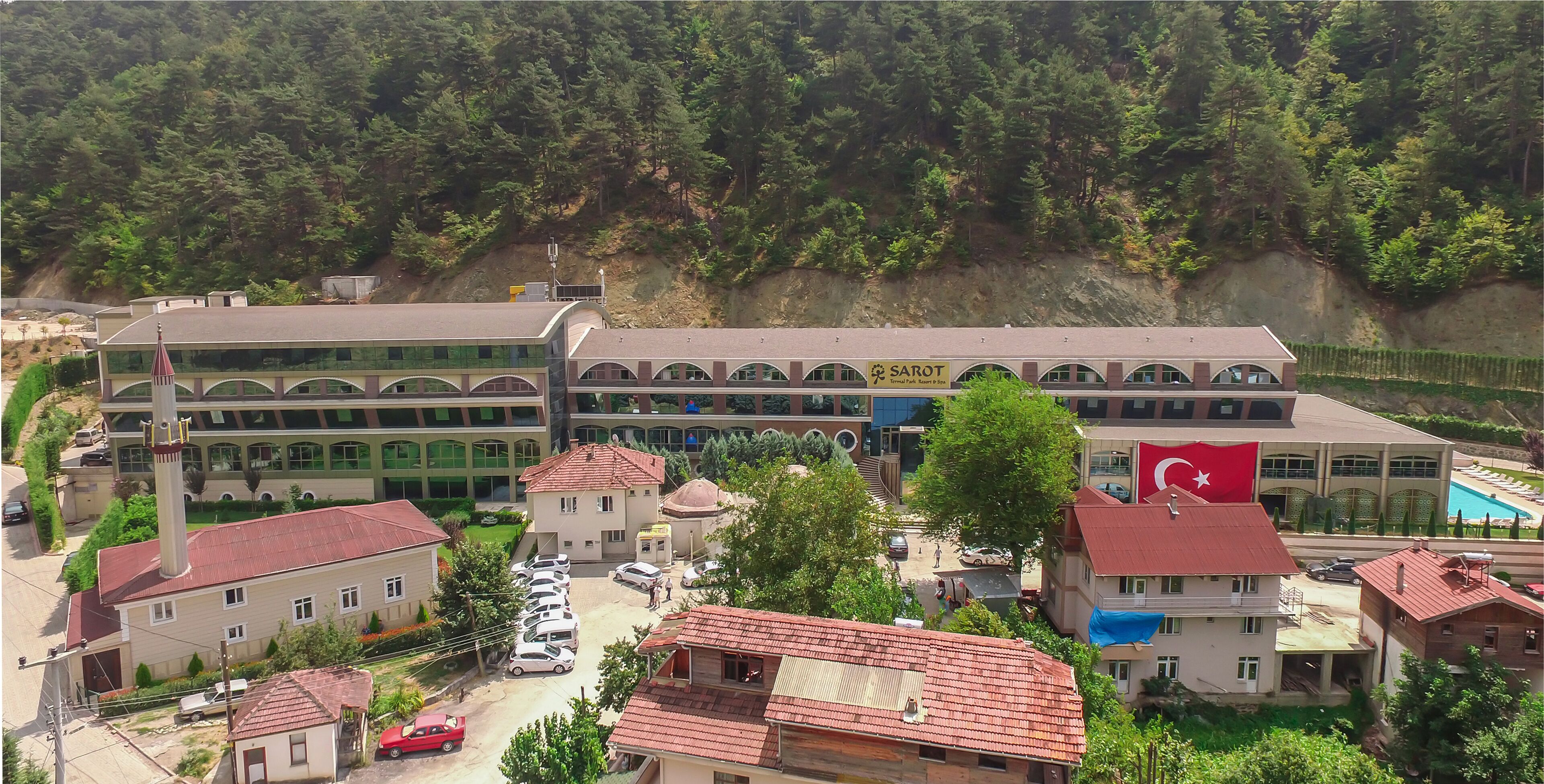Un edificio de varios pisos con un patio central, rodeado por edificios residenciales y una ladera boscosa.