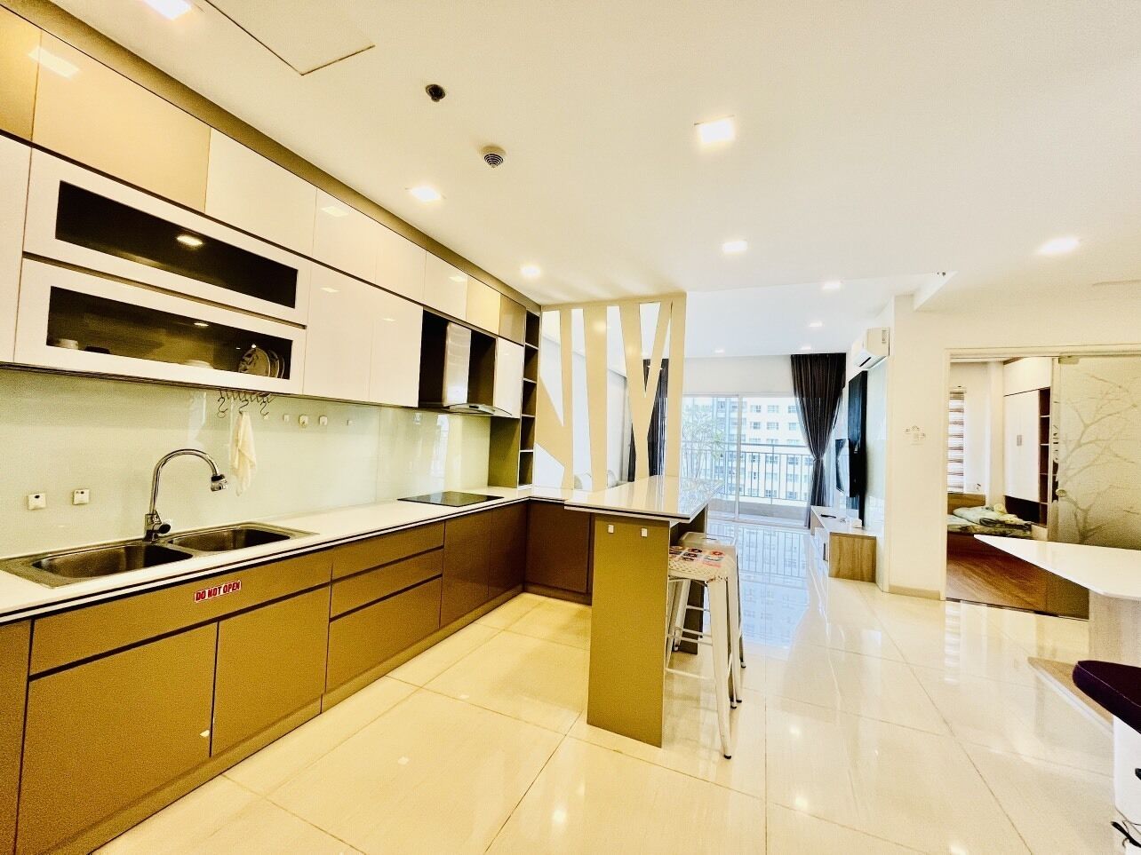 A modern kitchen with a central island, built-in appliances, and a view to the living area.