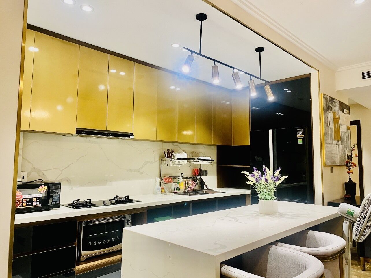 A modern kitchen with gold cabinets, a white countertop, and a built-in dishwasher.