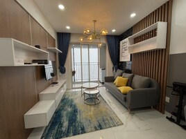 Una sala de estar moderna con un sofá gris, cojines amarillos, una mesa de centro y estanterías empotradas.