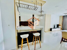 Una cocina moderna con armarios blancos, una encimera negra y dos taburetes blancos.