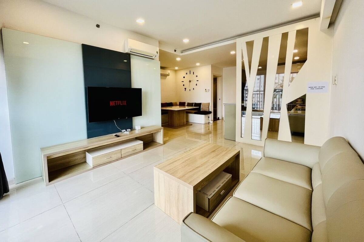 Ein modernes Wohnzimmer mit einem Flachbildfernseher, einem Holztisch und einem beigefarbenen Sofa.