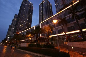 Vista nocturna de una zona urbana moderna con edificios altos, farolas y palmeras.