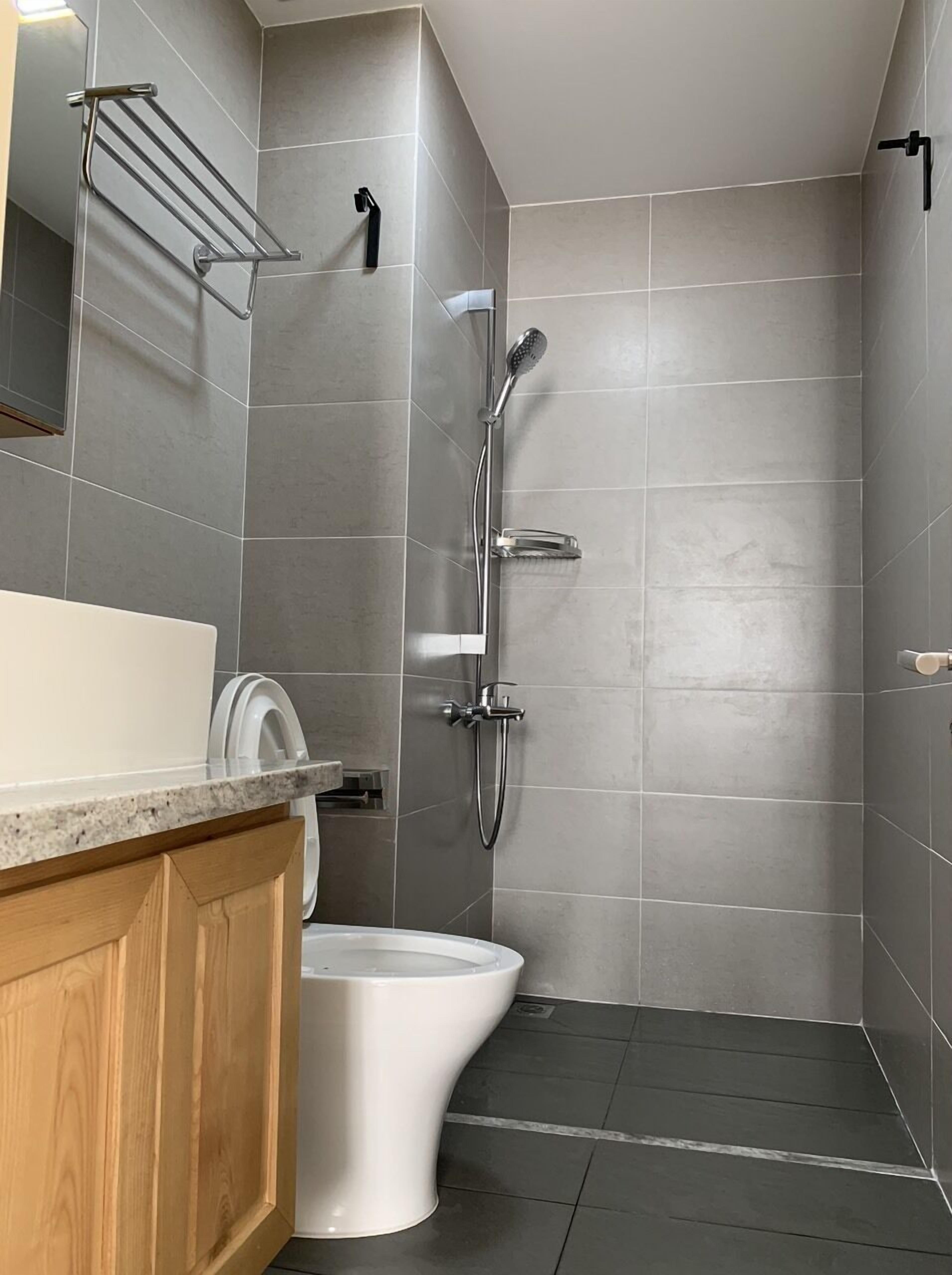 A modern bathroom with a shower, toilet, and a towel rack.