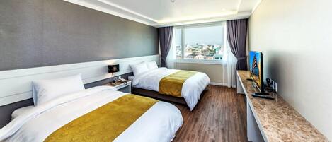 Una camera d'albergo con due letti, una scrivania, una televisione e vista sulla città.