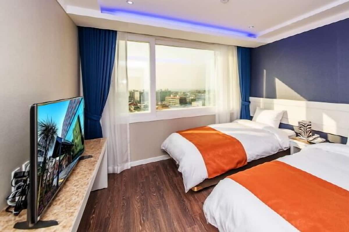 Une chambre d’hôtel avec deux lits, une télévision et une vue sur la ville.