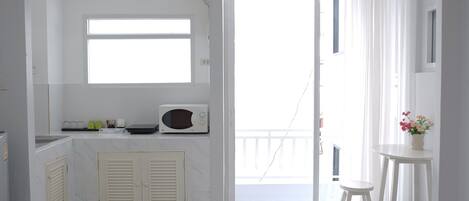 A small, bright room with a kitchen area, a toilet, and a balcony with a view.