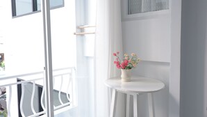 A white room with a small table and a vase of flowers. - Shan Boutique Hotel (Chiang Mai)