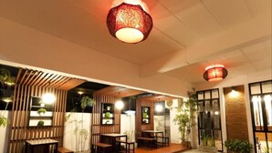 An outdoor seating area with wooden tables and chairs, surrounded by vertical wooden slats and potted plants. - Shan Boutique Hotel (Chiang Mai)