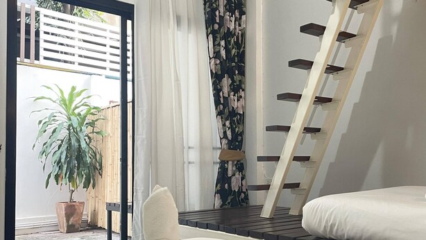 A bedroom with a bed, a wooden ladder, a potted plant, and a view of the outside. - Shan Boutique Hotel (Chiang Mai)