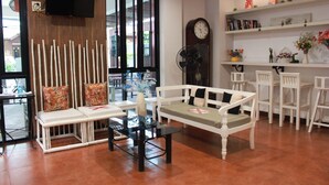 A modern interior with a sofa, chairs, a table, a TV, and a bookshelf. - Shan Boutique Hotel (Chiang Mai)