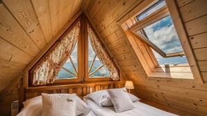 A wooden cabin bedroom with two beds, a skylight, and a view of the mountains. - Osada Kościelisko (Koscielisko)