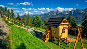 A wooden cabin with a swing set and a small pool, surrounded by lush greenery and mountains. - Osada Kościelisko (Koscielisko)