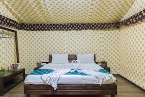 Cama bem arrumada com arranjo de toalha em formato de cisne, cabeceira de madeira e papel de parede estampado.