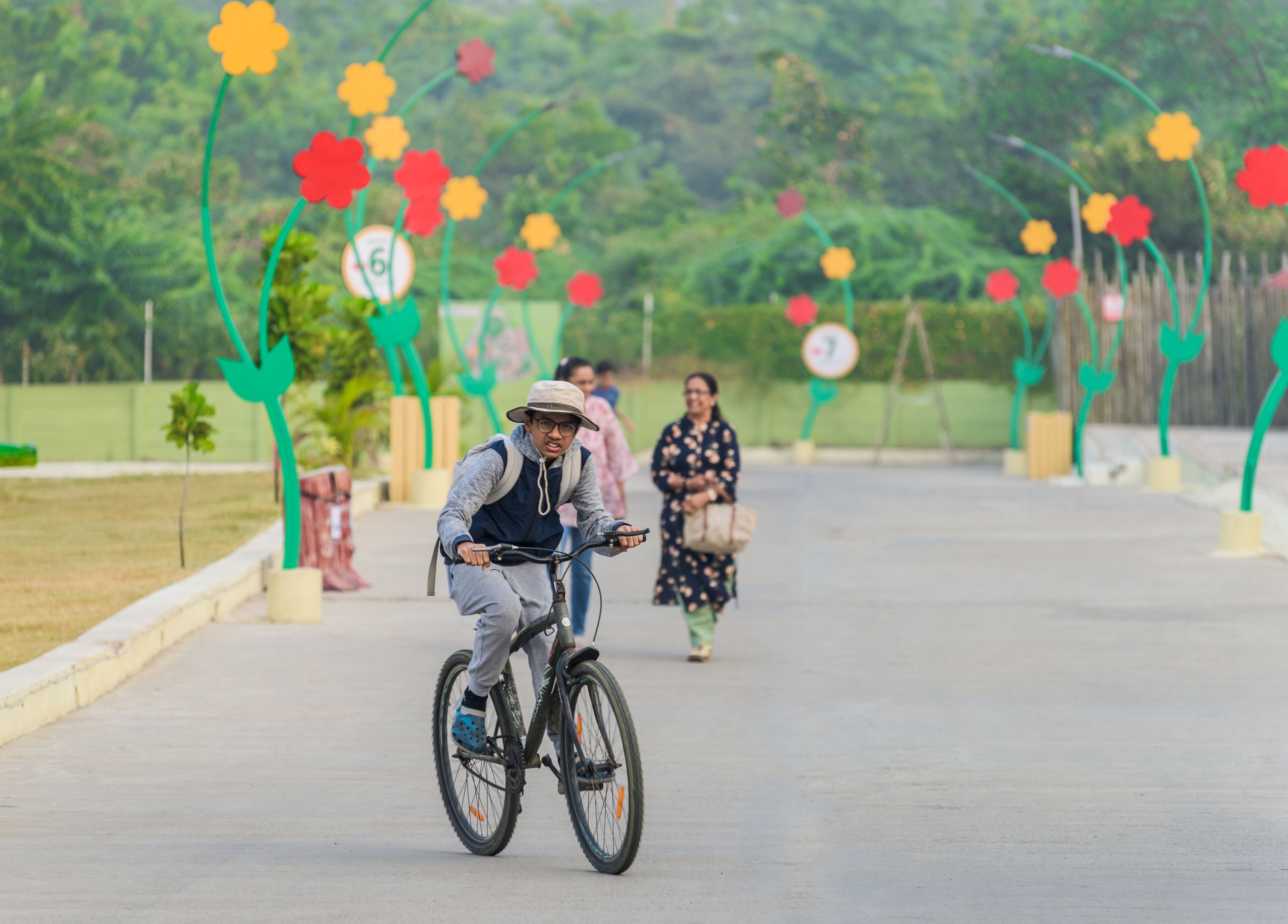 Una persona pedaleando en un camino pavimentado, con arcos decorativos de flores al fondo.