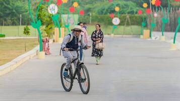 Una persona pedaleando en un camino pavimentado, con arcos decorativos de flores al fondo.