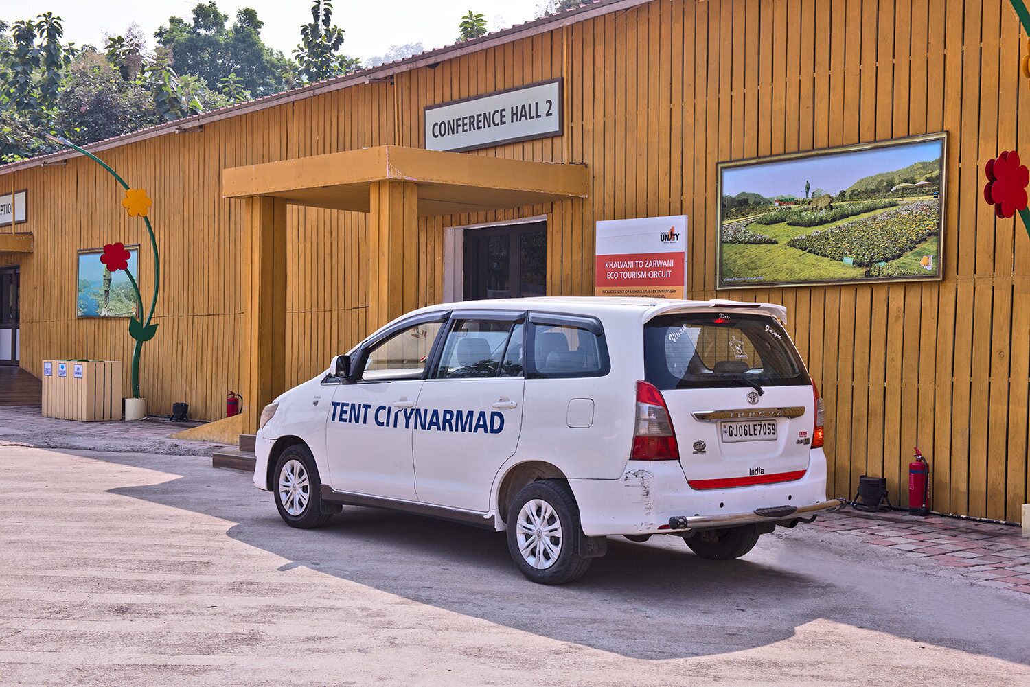 A white van parked in front of a wooden building labeled "CONFERENCE HALL 2".