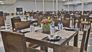 Un amplio comedor con varias mesas y sillas, botellas de agua y centros de mesa florales.