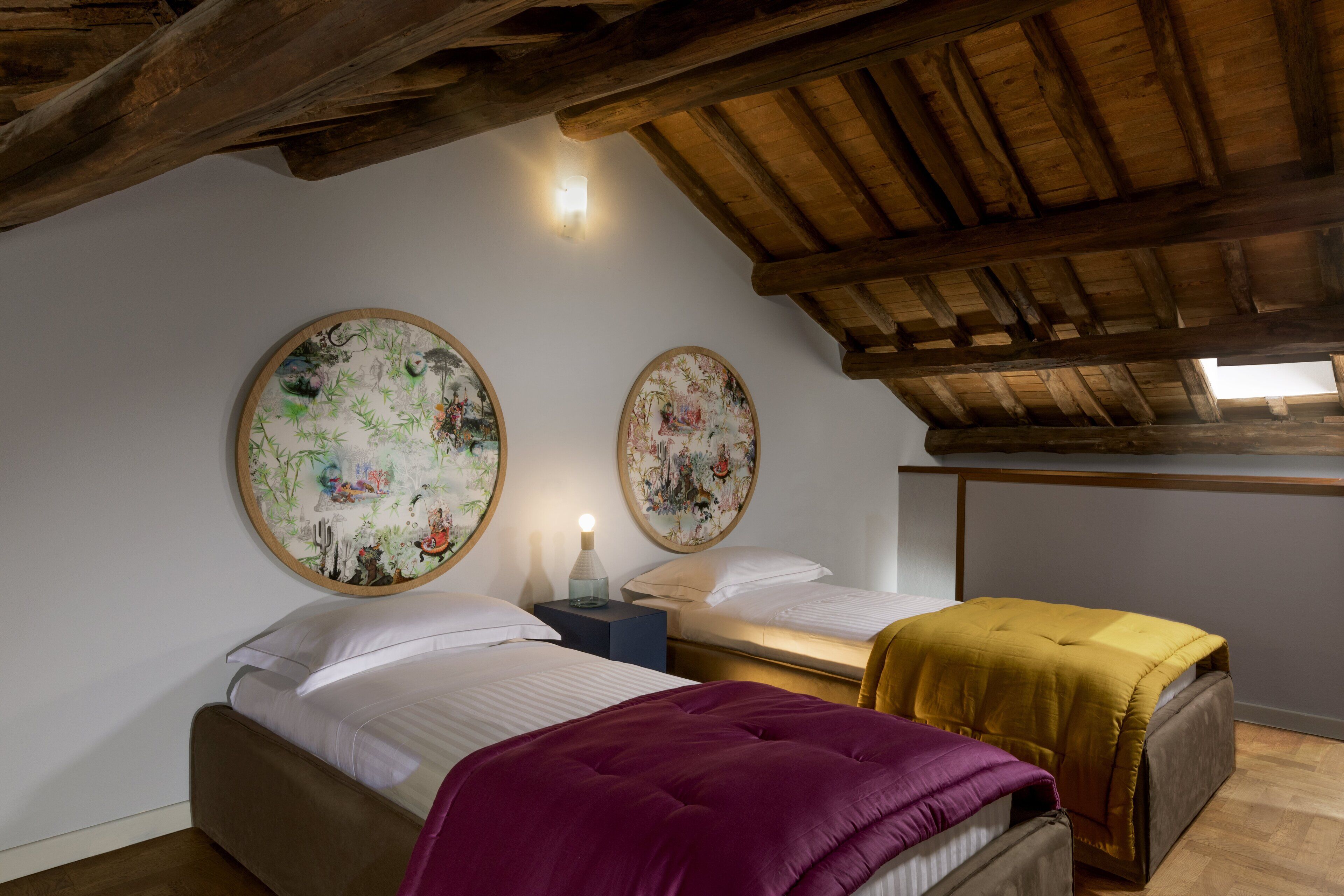Un dormitorio con dos camas, vigas de madera en el techo y dos obras de arte colgadas en la pared.