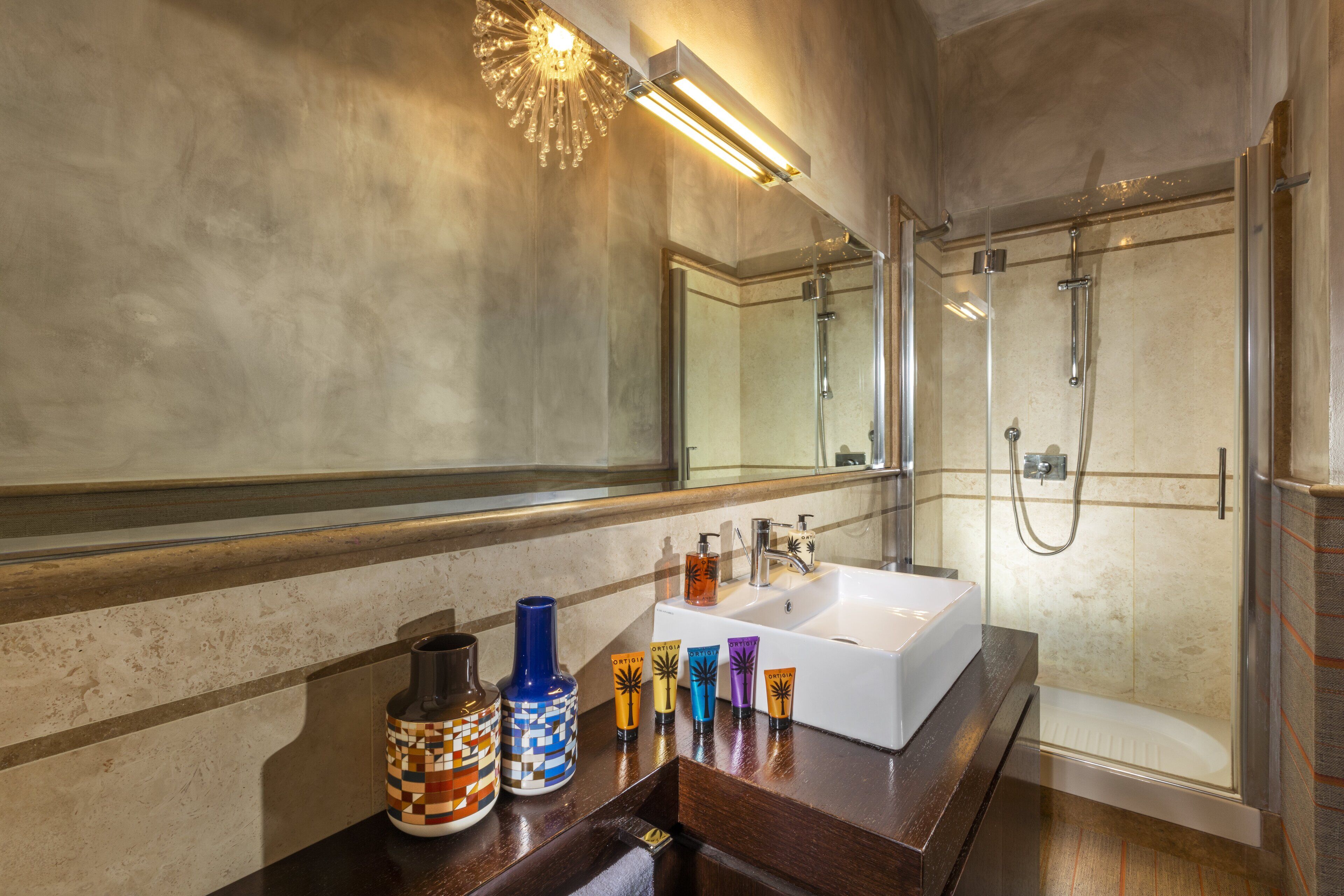 Une salle de bain moderne avec un grand miroir, un lavabo blanc et une douche à parois de verre.
