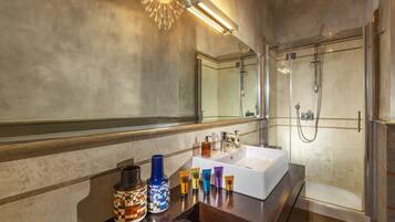 Une salle de bain moderne avec un grand miroir, un lavabo blanc et une douche à parois de verre.