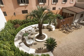 A courtyard with a palm tree, outdoor seating, and bicycles.