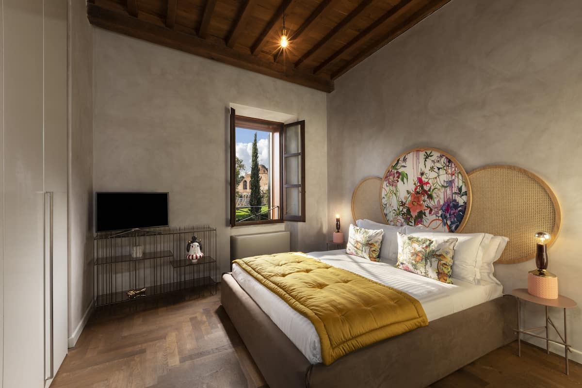 Une chambre à coucher avec un lit, un téléviseur posé sur un meuble, une fenêtre avec un volet ouvert et une décoration murale.