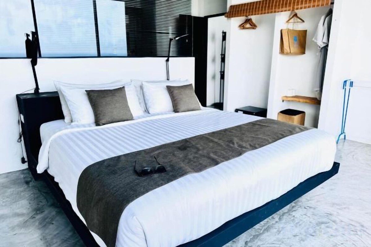 A modern bedroom with a large bed, bedside tables, and a hanging light fixture.