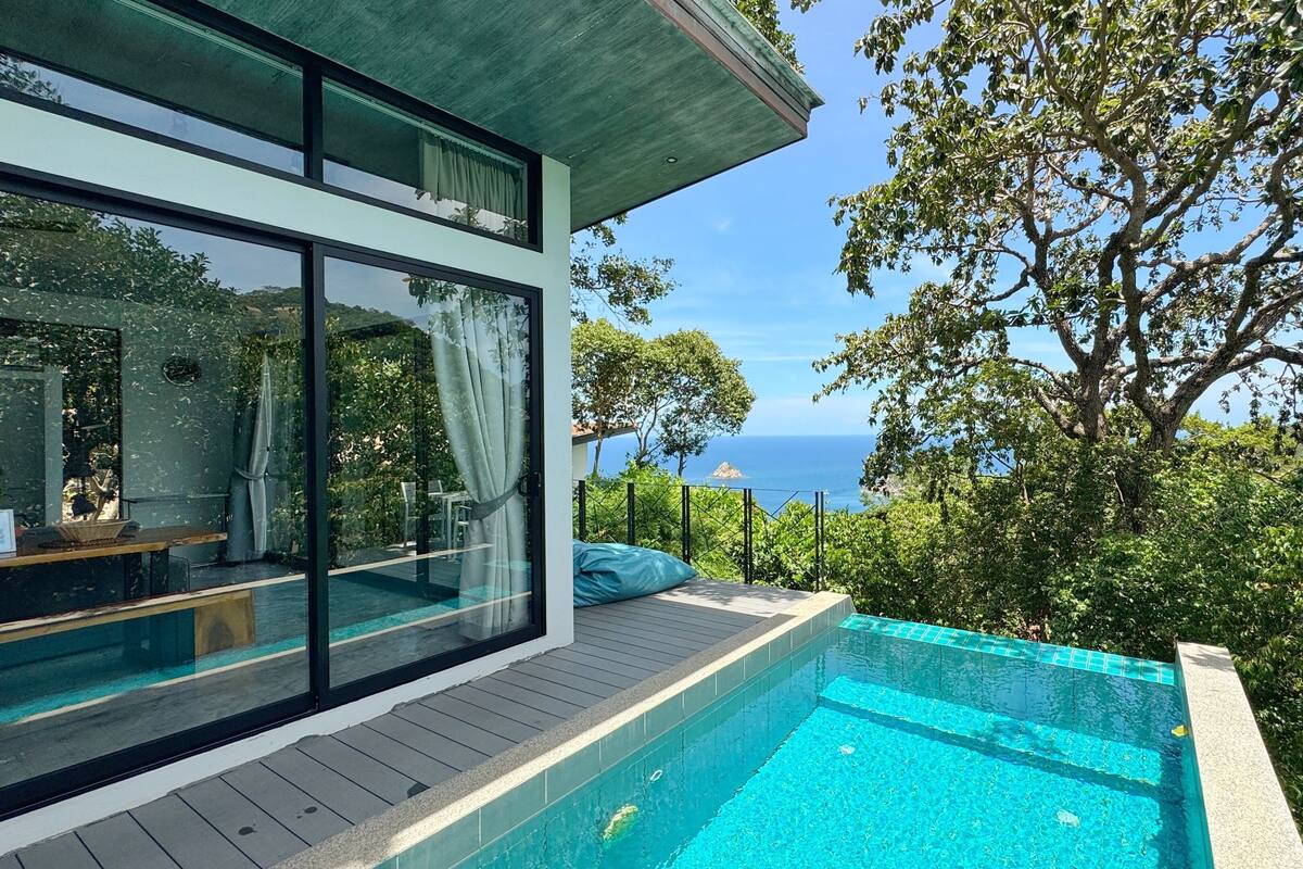Ein modernes Haus mit Swimmingpool, großen Fenstern und Meerblick.