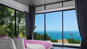Een moderne slaapkamer met een groot bed, uitzicht op zee en een balkon.