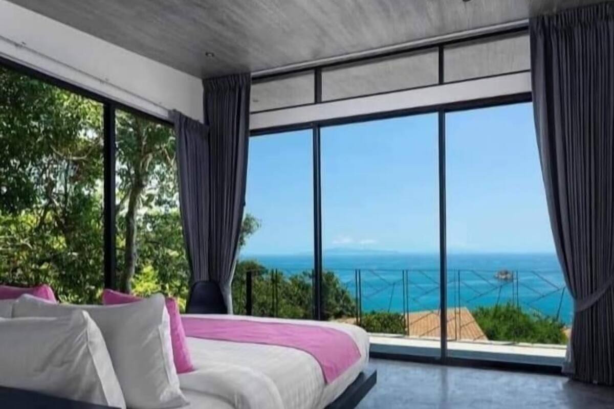 Ein modernes Schlafzimmer mit einem großen Bett, Meerblick und einem Balkon.