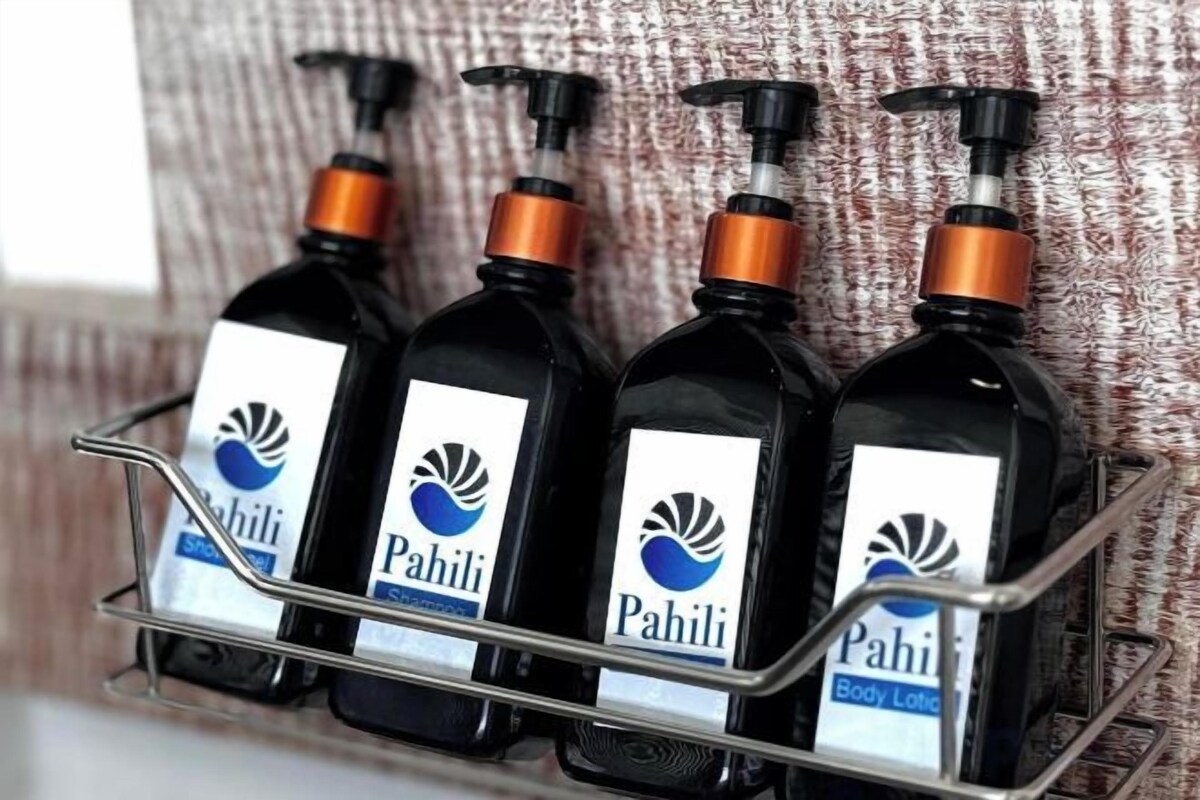 Un présentoir métallique contenant quatre bouteilles de lotion pour le corps de la marque Pahili.