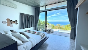 Een moderne slaapkamer met een groot bed, uitzicht op de oceaan en een balkon.