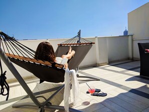 A person relaxing in a hammock on a rooftop terrace with a view of the city skyline. - Basco Knez Mihailova Apartments (Belgrade)