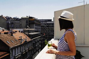 A person standing on a balcony overlooking a cityscape with multiple buildings. - Basco Knez Mihailova Apartments (Belgrade)