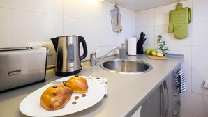 Eine moderne Küche mit Toaster, Wasserkocher, Spüle sowie einem Teller mit Brot und Schokoladenstückchen.