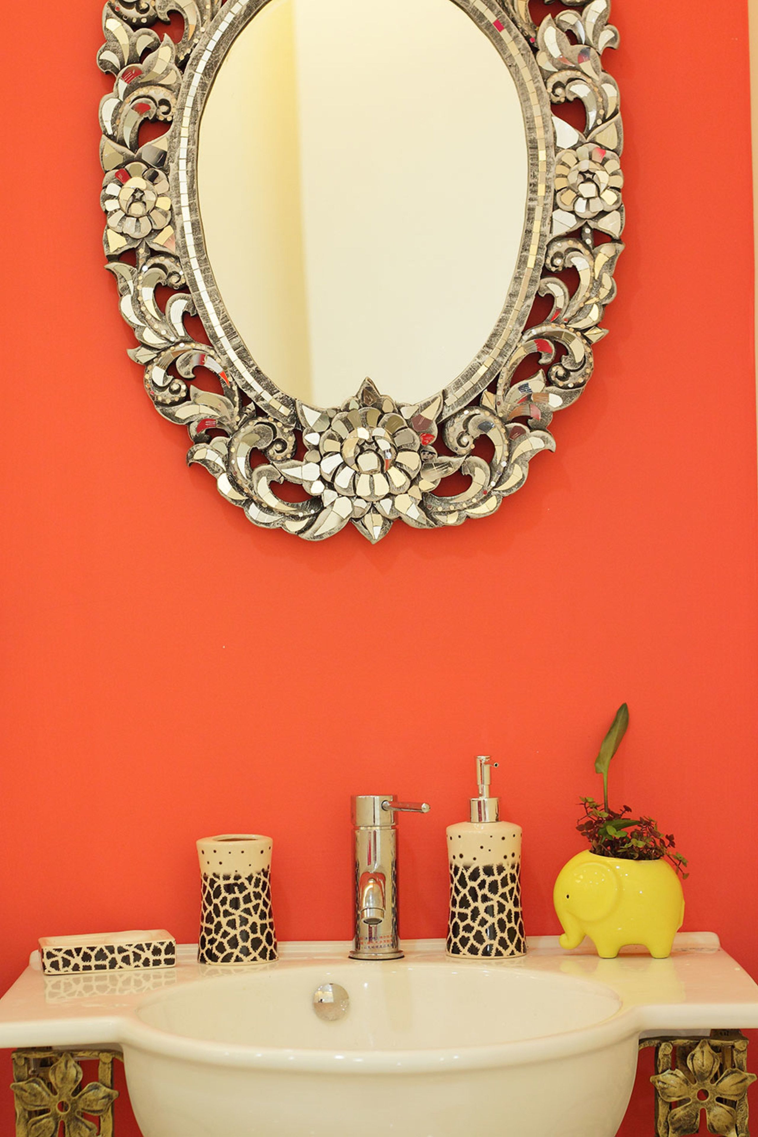 A bathroom with a white sink, a mirror with a decorative frame, and two patterned soap dispensers.