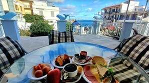 A breakfast table with various food items and a view of the cityscape. - Dolphin Hotel (Skopelos)