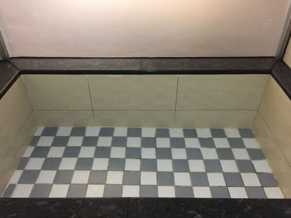 Un baño con paredes de azulejos y un suelo con diseño de cuadros.