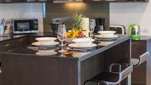 Een moderne keuken met een centraal eiland, donkere kastjes, een magnetron en een fruitschaal.