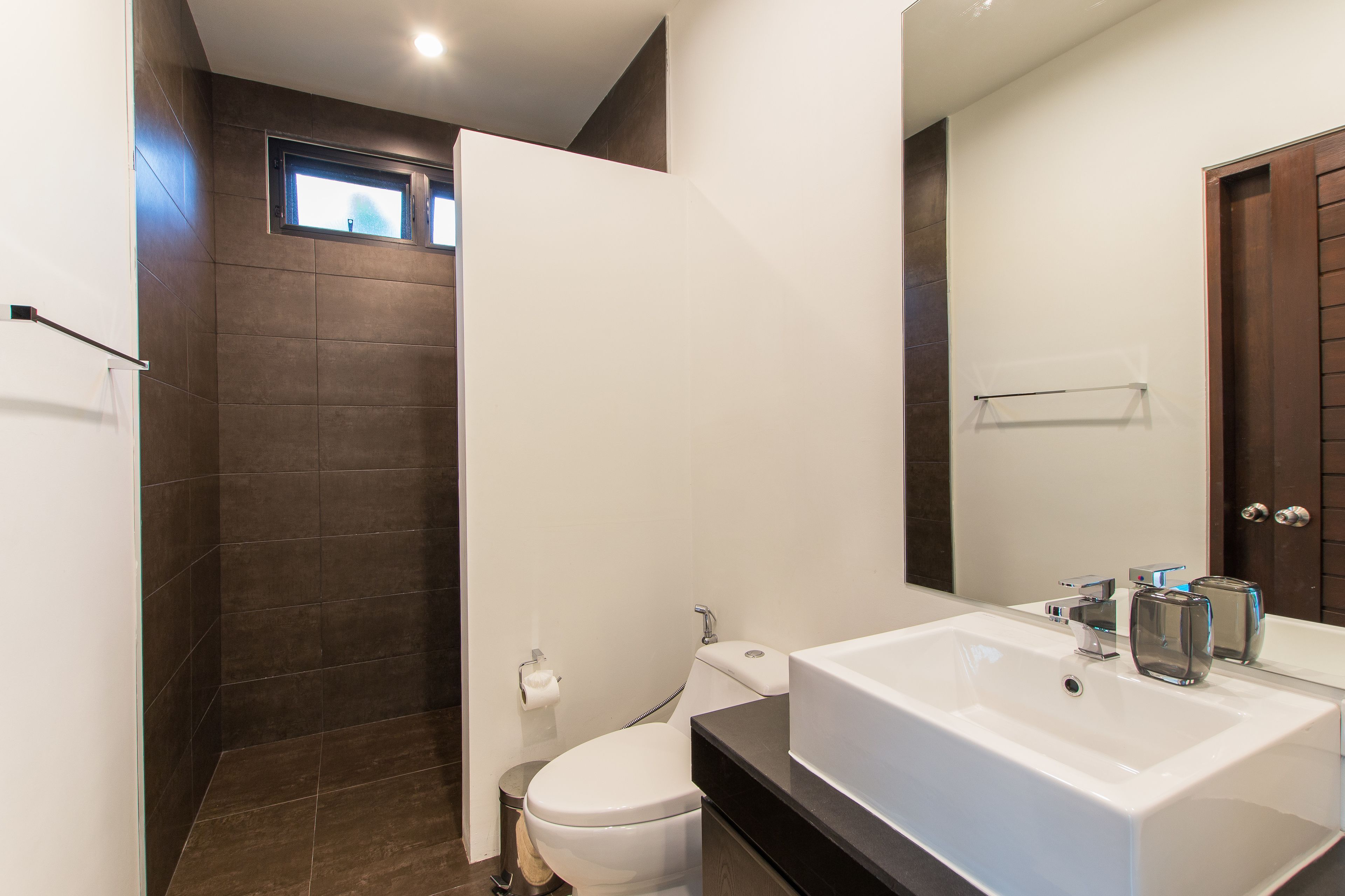A modern bathroom with a large sink, toilet, and shower area.