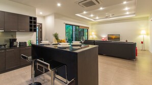 Een moderne keuken met een centraal eiland, barstoelen en een zithoek met een bank en tafel.