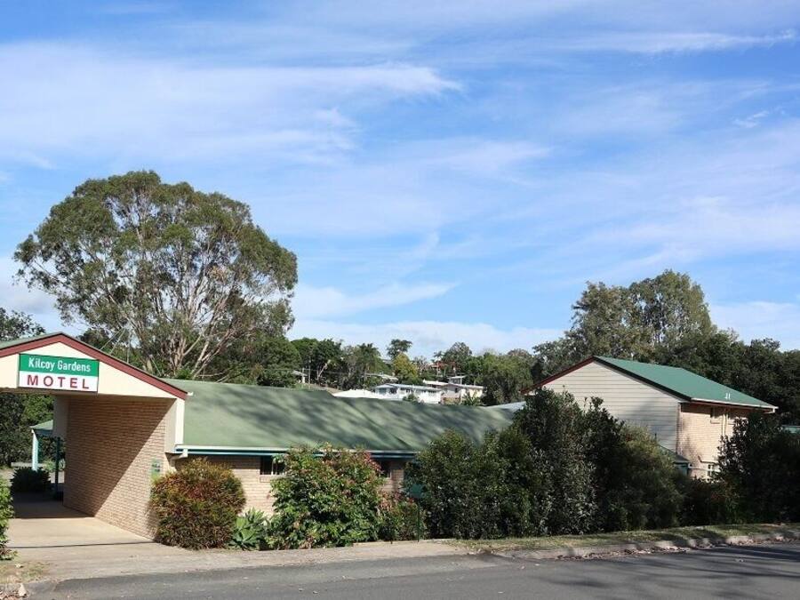 Un motel llamado 'Kilcay Gardens' con techo verde y fachada de ladrillo.