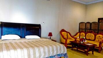 A hotel room with a large bed, a sofa, a small table, and a decorative chair.