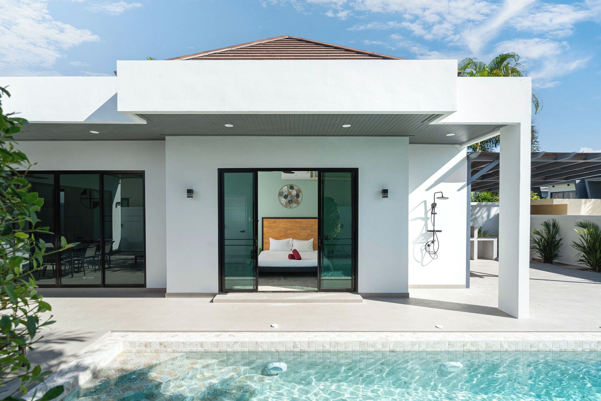 Ein modernes Haus mit Swimmingpool, ein Schlafzimmer mit Bett und Blick auf den Pool sowie eine Terrassenanlage.