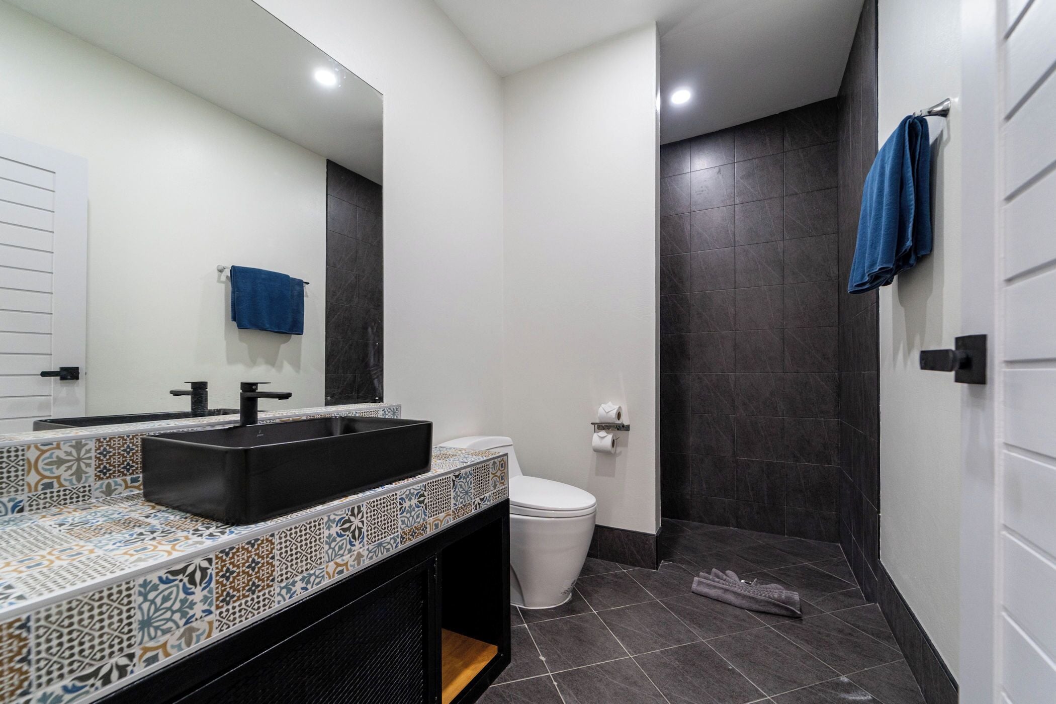 Casa de banho moderna com lavatório preto, sanita e zona de duche.