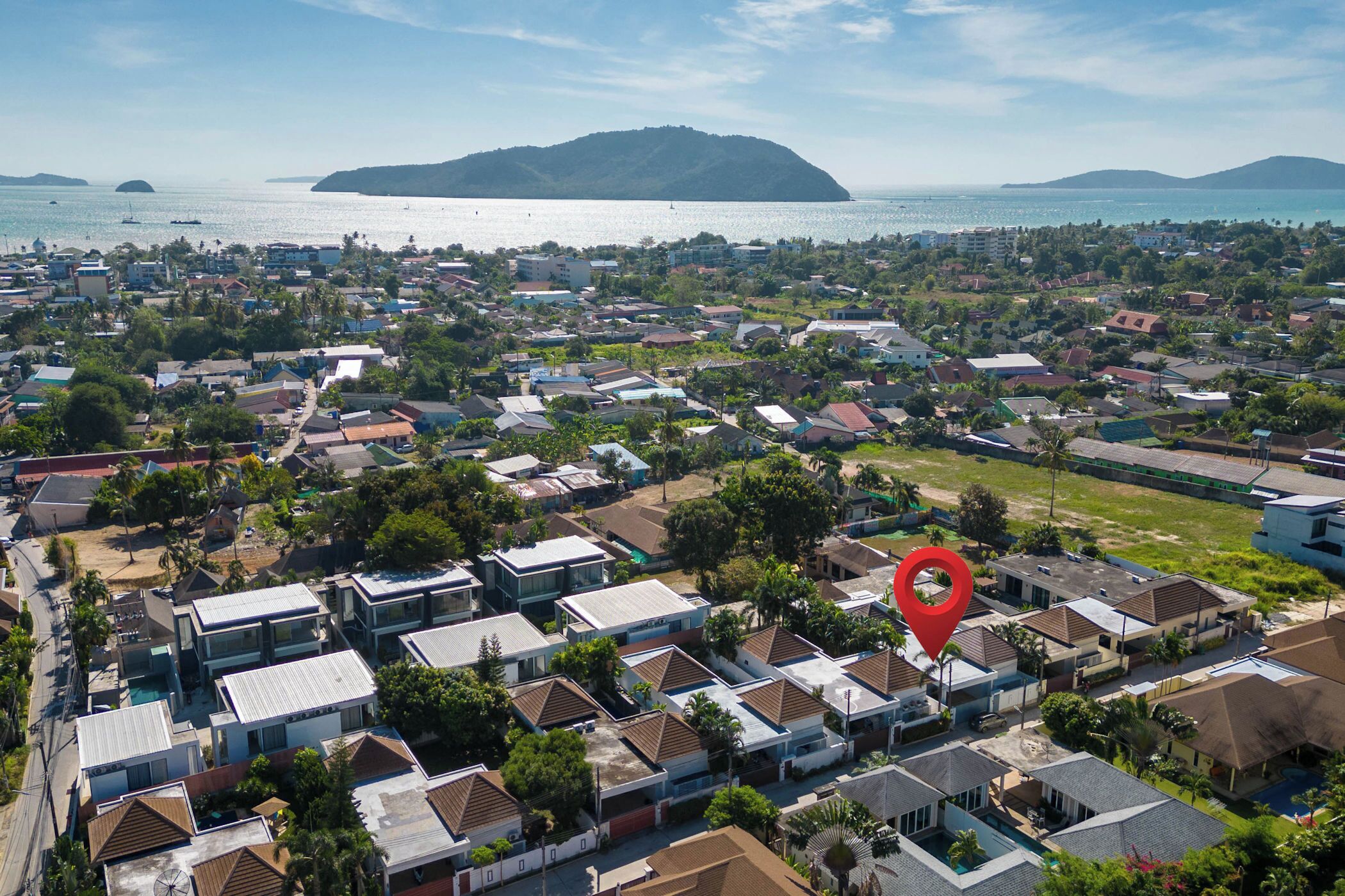 An aerial view of a residential area with houses, a body of water, and a mountain in the background.