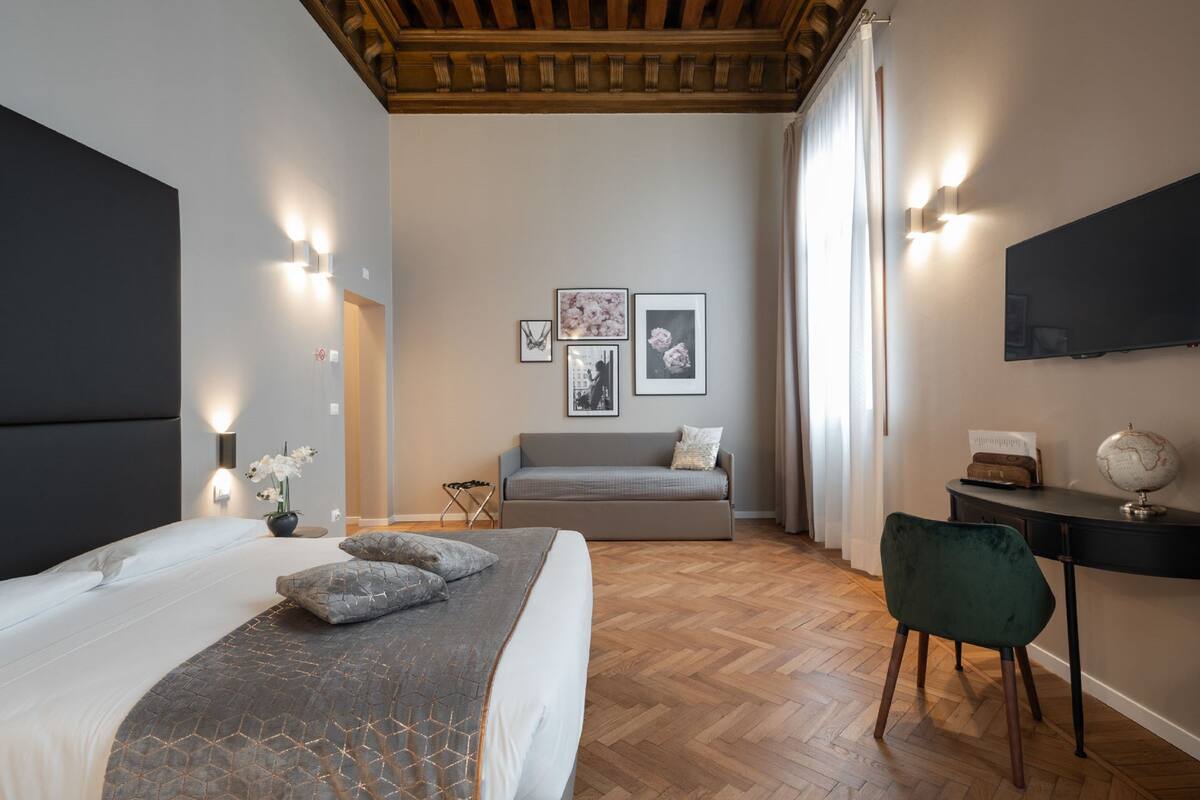 A modern bedroom with a large bed, a desk, a chair, and a sofa.