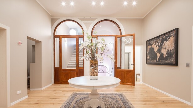 Un couloir avec une table ronde, un tapis à motifs, un plancher en bois et une carte du monde accrochée au mur.
